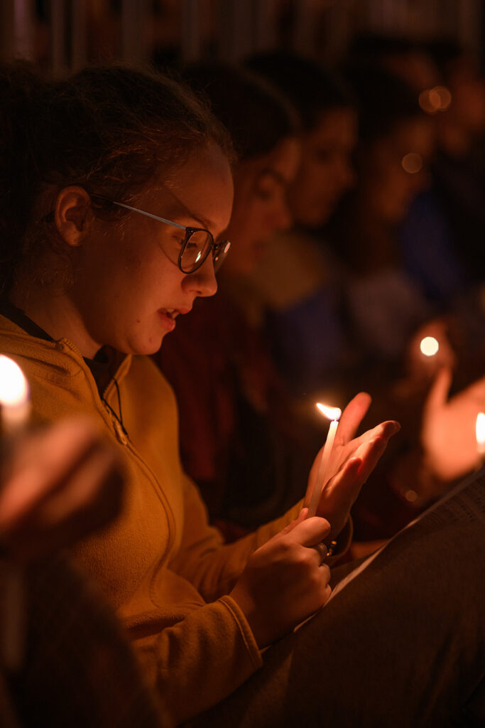 Una giovane legge i canti alla luce di una candela durante la preghiera