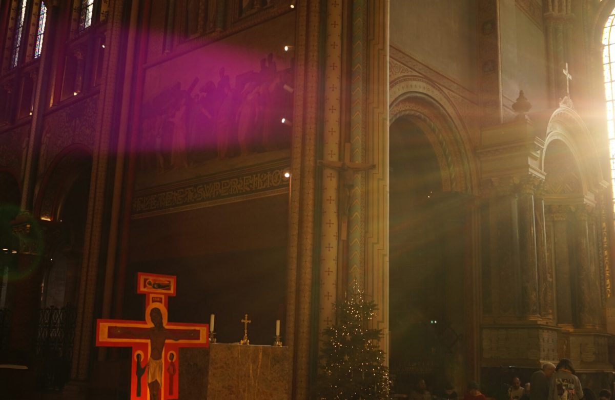 La croce di Taizé e le candele accese durante la preghiera, in una chiesa illuminata dalla luce